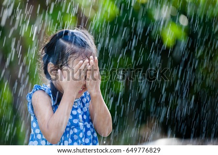 Happy asian little girl having fun to play with the rain