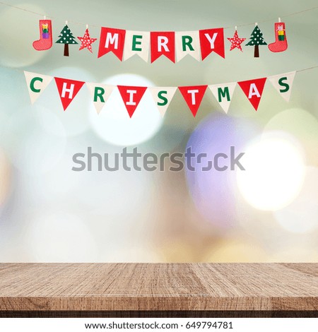 Merry Christmas bunting flag over empty wood table and blur festive bokeh light background, greeting card banner
