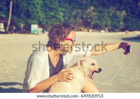 Happy young beautiful funny girl on the beach doing selfie with a dog. Vacation, travel, joy, freedom, internet, technology concept