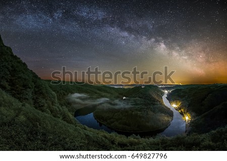 The Milky Way over the Saar Loop as seen from the viewpoint Cloef at Orscholz near Mettlach in Germany. Royalty-Free Stock Photo #649827796