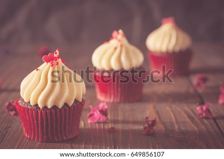 red velvet cupcakes with cream cheese icing decorate with dry flowers on wood board in soft tone