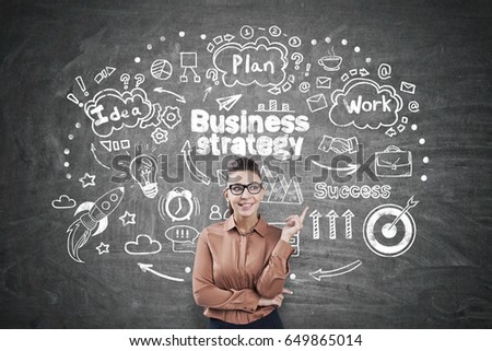 Young businesswoman wearing a brown blouse and glasses is pointing at a business strategy sketch drawn on a blackboard. Concept of planning