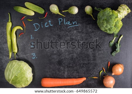 Fresh vegetables with diet plan on black chalk board background top view 