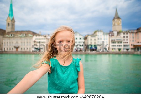 Adorable little girl taking selfie outdoors in Zurich, Switzerland. Closeup portrait of kid background of beautiful city