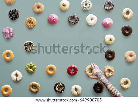 Hand with tattoo reaching for donut
