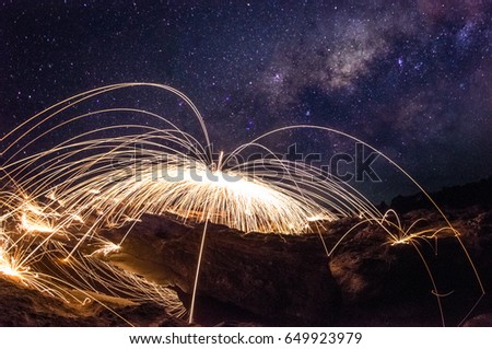 Amazing fireworks, Burning and spinning steel wool on the rock, Showers of hot glowing sparks, Long exposure photo background, Grand canyon of Thailand, The Milky Way galaxy pointing on a bright star.