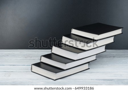 Open black and White books on wooden table, black board background. Back to school. Education business concept