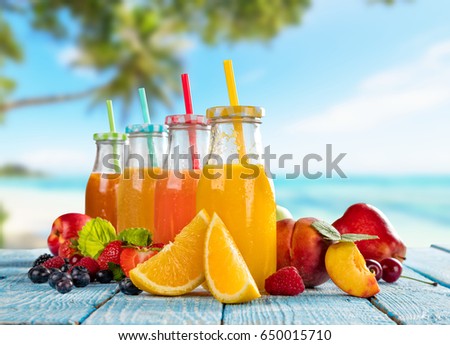 Fresh smoothie drinks placed on wooden planks, blur tropical beach on background. Summer drinks and beach vacation background