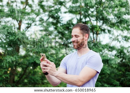 Casual guy in a park taking a photo with his mobile