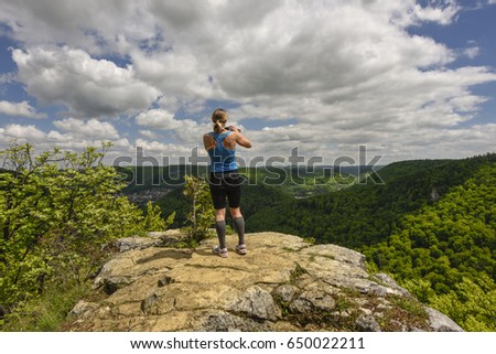Sportive woman taking a photograph of a beautiful panorama, taking picture with mobile phone / smartphone / handy,  Bad Urach, Swabian Alps, Baden-Württemberg, Germany