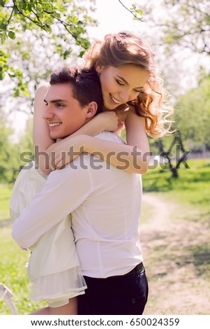 bride and groom with a bouquet of red peonies in the summer standing in a field with blooming apple trees