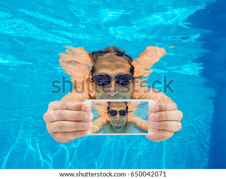 Portrait of a happy man with smart phone under water. Selfies