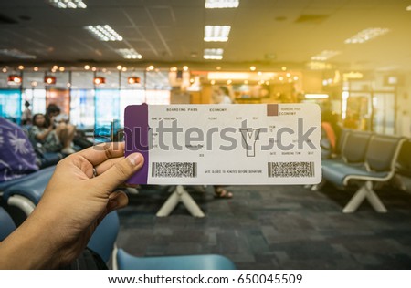 Boarding pass on hand with blur airport terminal background in traveler concept. Royalty-Free Stock Photo #650045509