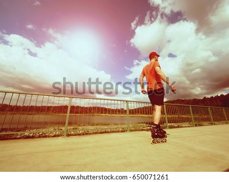 Vintage tone filter effect color style. Sportsman  with inline skates ride in summer park close to handrail, outdoor roller skater on park bridge 