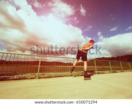 Vintage tone filter effect color style. Sportsman  with inline skates ride in summer park close to handrail, outdoor roller skater on park bridge 