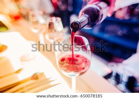 WARNING: small grain in 100% zoom visable (4K resolution),. Also shallow depth of field. Macro close up MAN or WAITER or SOMMELIER HAND pouring red wine in glass with blurred background 