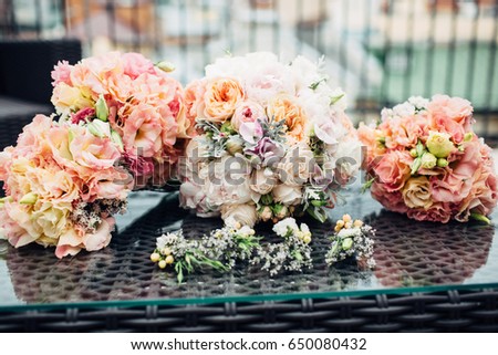 Bouquets of peonies and white flowers lie on glass table outside