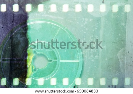 Old blue film reel in film strip frame on a scratched and rusty metal background.