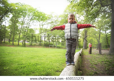 Little boy walking on a log in the park.  child on the balance beam. Copy space for your text Royalty-Free Stock Photo #650111275