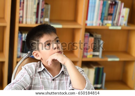 Portrait of asian schoolboy thinking In the library
