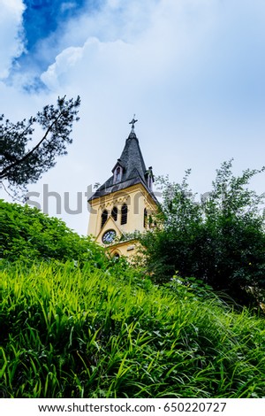 A church on top of a lush green hill with beautiful blue sky as background