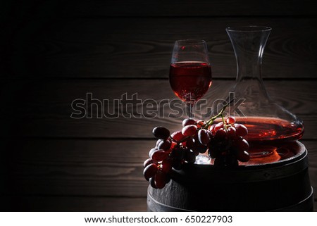 Red wine and a bunch of grapes on a wooden barrel