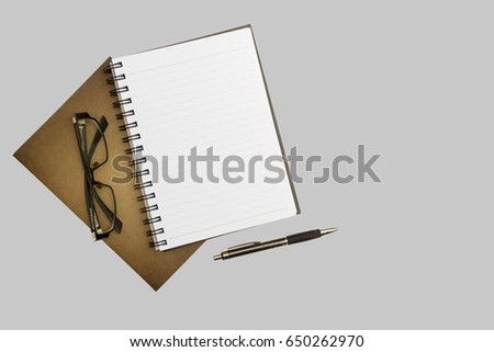 Top view blank notebook, pen and glasses on gray desk background.with copy space.on isolated