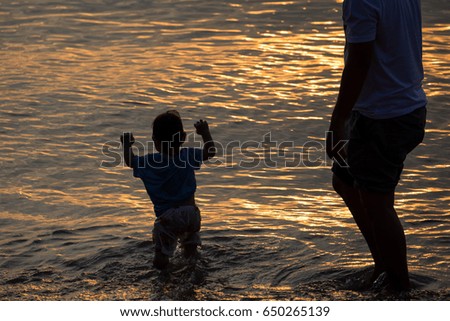Father and little daughter walking on sand beach at sunset