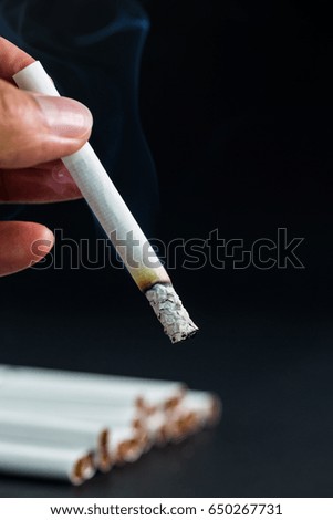 man hand with Cigarettes with a soft focus background is black