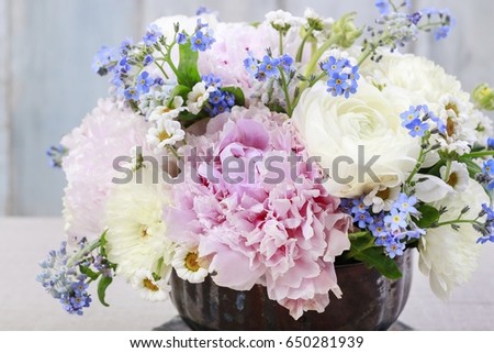 Floral arrangement with pink peonies, ranunculus flowers, white chrysanthemums, matricaria forget me not and bluebells (muscari).
