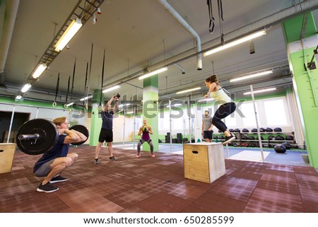 fitness, sport and exercising concept - group of people training with different equipment in gym