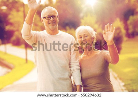 family, age, tourism, gesture and people concept - senior couple waving hands in city park