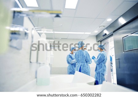 surgery, medicine and people concept - group of surgeons in operating room at hospital talking and preparing to operation Royalty-Free Stock Photo #650302282
