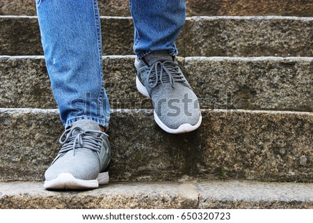 
Men's legs in gray sneakers and blue jeans on the street, On the stairs 