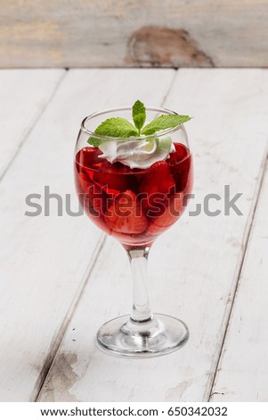 Strawberry jelly, strawberry and ice cream with mint in a glass on a wooden table, country style