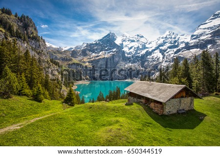 Amazing tourquise Oeschinnensee with waterfalls, wooden chalet and Swiss Alps, Berner Oberland, Switzerland.  Royalty-Free Stock Photo #650344519