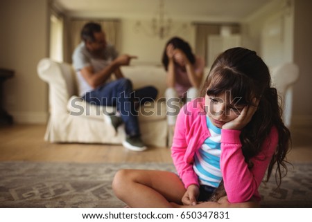 Sad girl listening to her parents arguing at home Royalty-Free Stock Photo #650347831