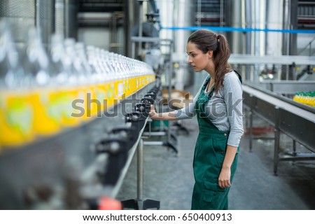Female factory worker inspecting production line at drinks production factory Royalty-Free Stock Photo #650400913