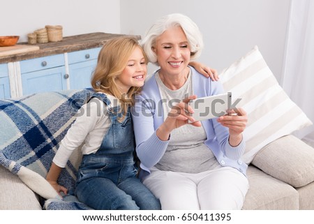 Granddaughter taught grandmother how to make self-photos, selfies on mobile or smart phone. Pretty ladies taking photos while smiling for camera.