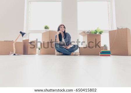 Low angle photo of brunette young woman in light modern apartment, looking up and dreaming, planning how she will organize the space in new apartment