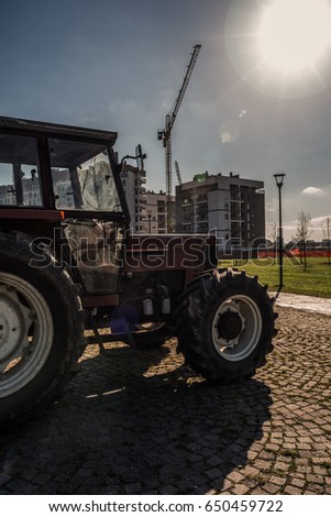 Tractor at the break before getting back on the harvesting of cut grass in the city park.  Back-light image.