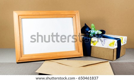 Wooden frame with gift box and envelope on the table.