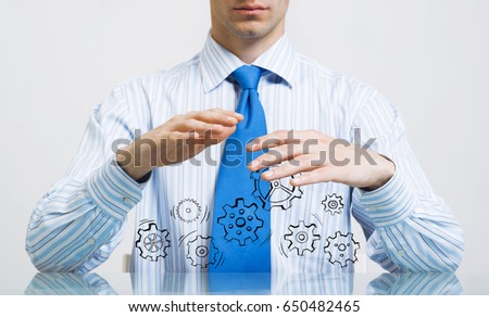 Close up of businessman sitting at table and showing gear mechanism in palms