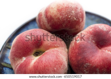 Ripe red hybrid fig peaches on blue plate. Close up food. Flatlay on white background