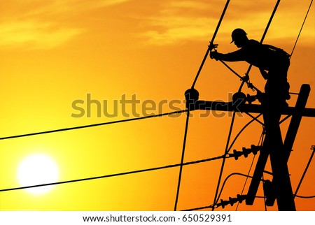 Shadow electricians repairing wire on electric power pole at the sunsetbackground blur. Royalty-Free Stock Photo #650529391