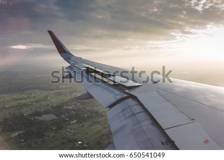 Wing of an airplane flying above the clouds at sunset ( Filtered image processed vintage effect. )
