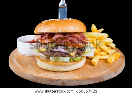 Burger with french fries on a round wooden board