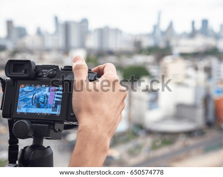 Selected focus on photographer's hand with camera, blur of city background