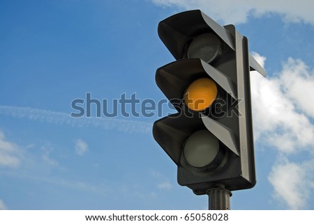 Amber color on the traffic light with a beautiful blue sky in background