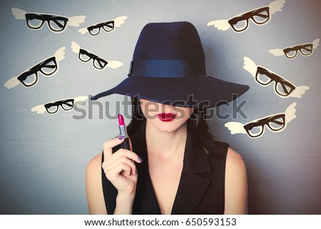 portrait of beautiful young woman in hat holding lipstick on the wonderful grey studio background